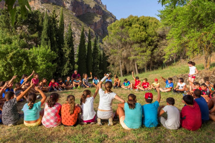 niños en una actividad al aire libre en la sierra hacen un círculo sentados