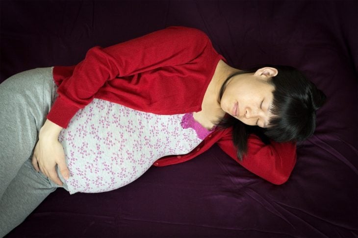 mujer asiática embarazada acostada