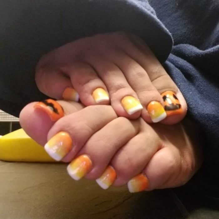 Chica con las uñas de los pies con acrílico y diseño de calabazas 