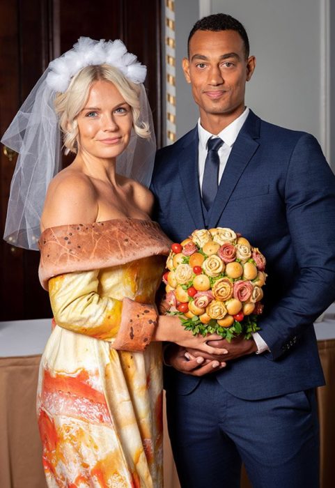 Chica usando un vestido de novia con estampado de pizza y un ramo de carnes frías con pan