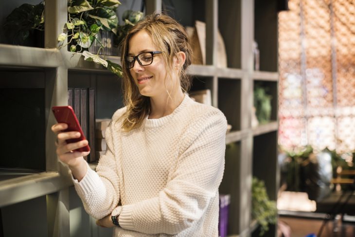 Mujer viendo su celular y sonriendo un poco