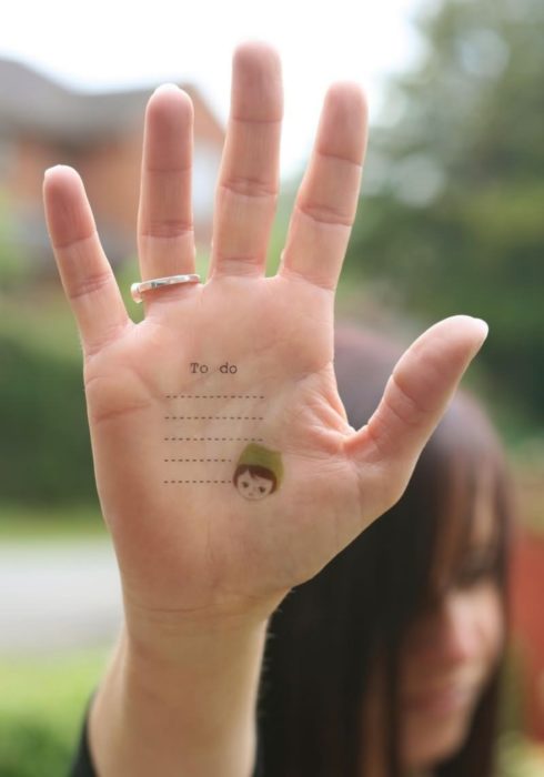 Chica con un tatuaje en las palmas de las manos en forma de lista para no olvidar los pendientes 