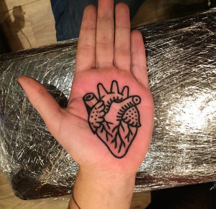 Chica con un tatuaje en las palmas de las manos en forma de un corazón 