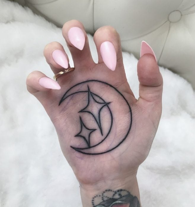 Chica con un tatuaje en las palmas de las manos en forma de luna y estrellas 