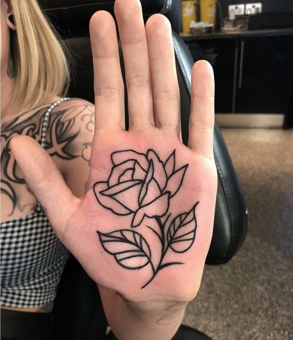 Ragazza con un tatuaggio sui palmi delle mani a forma di rosa 