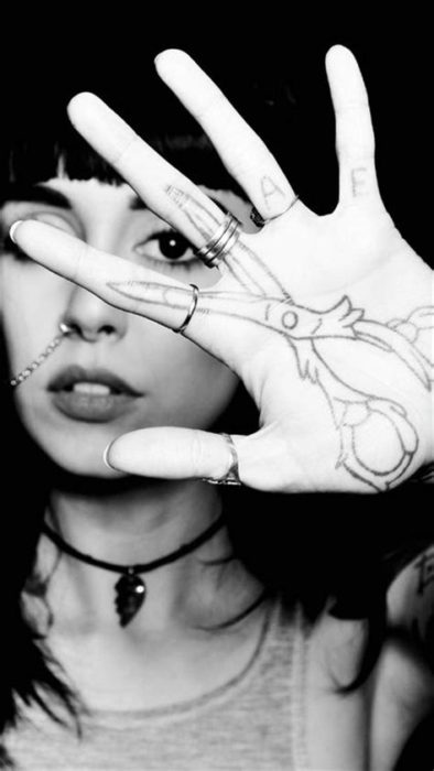 Chica con un tatuaje en las palmas de las manos en forma de unas tijeras 