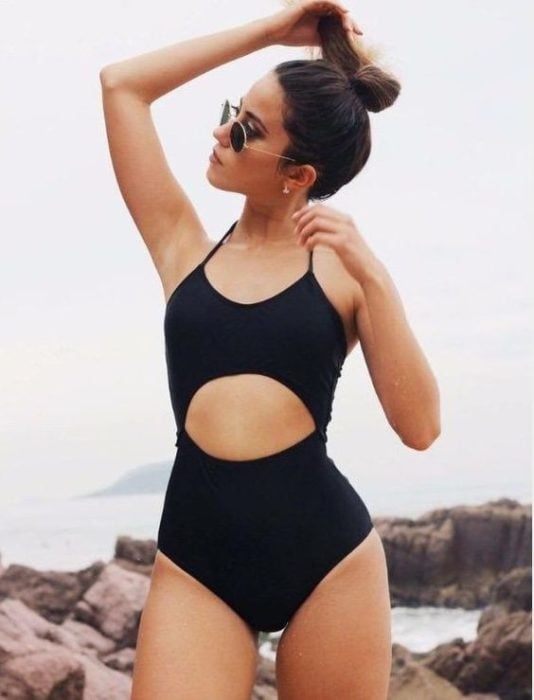 Chica usando un traje de baño de color negro con un corte en el abdomen