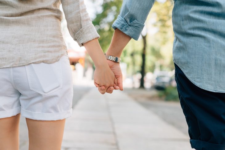 manos de una pareja que camina por una banqueta tomados de la mano