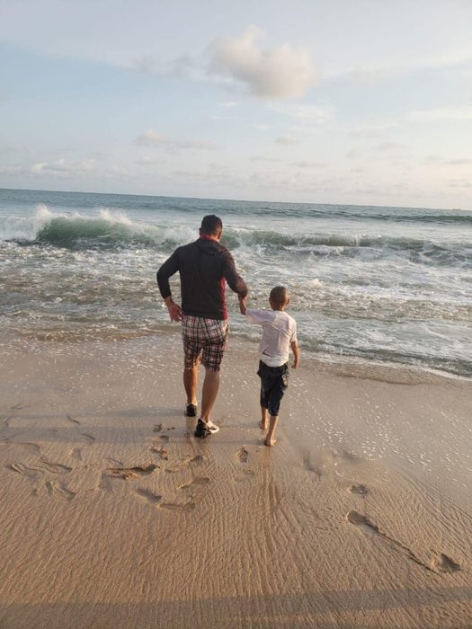 Jonathan caminando por su padre a la orilla del mar