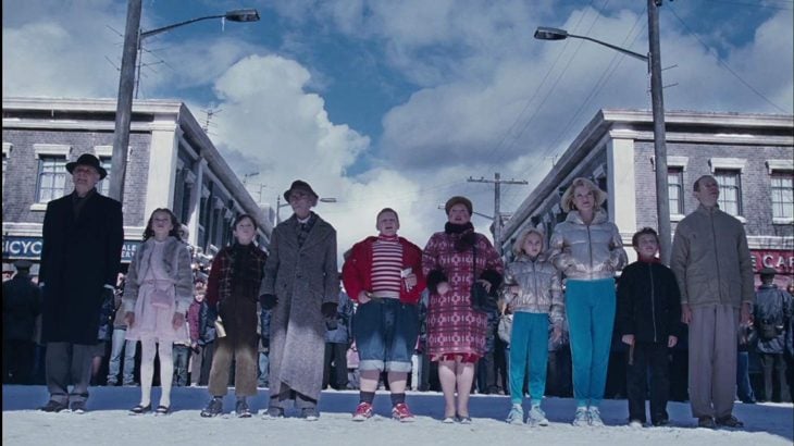 Niños junto a sus padres parados frente a la fábrica de Willy Wonka, escena de Charlie y la fábrica de chocolate