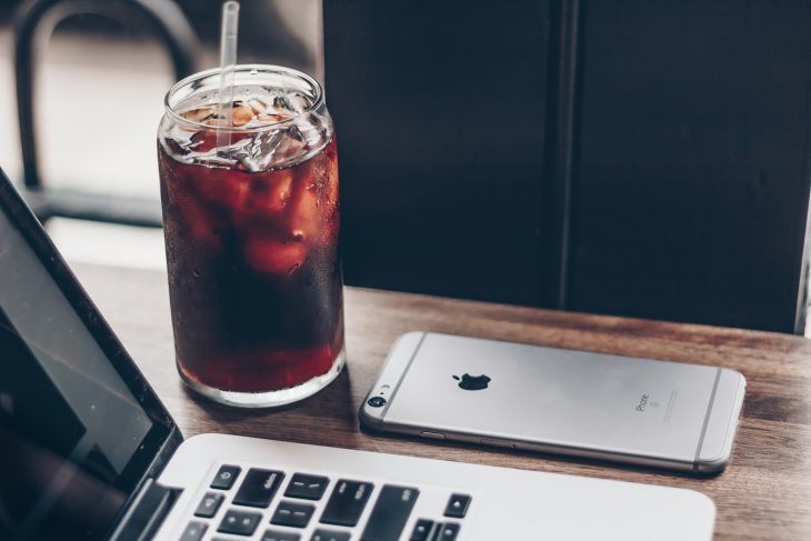 tazza di vetro con cocacola sulla scrivania con cellulare e computer