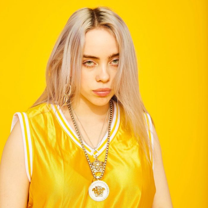 Billie Eilish posando para una sesión de fotos mientras usa un traje de color amarillo