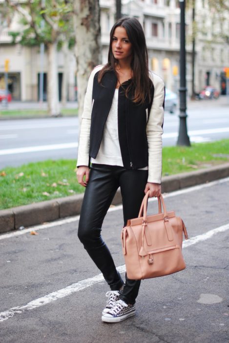 Chica parada en la calle durante una sesión de fotos y usando un outfit negro y bolsa de color rosa 