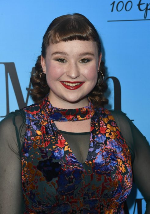 Julia Lester en una alfombra roja, llevando un palazo a flores para High School la serie