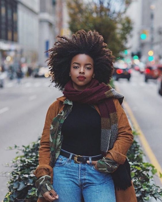 Chica afroamericana con cabello chino esponjado, posando para fotografía en la calle