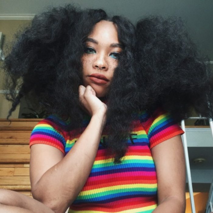 Chica afroamericana con rasgos asiáticos, ojos rasgados y pecas, con cabello chino, esponjado y con frizz