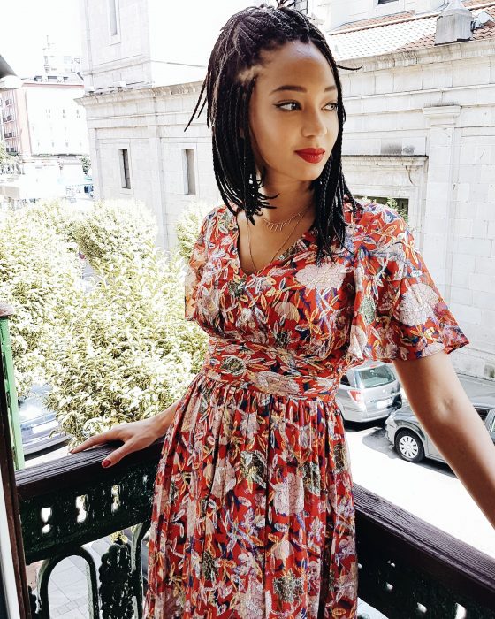 Chica afroamericana con peinado de trenzas hasta los hombros y con vestido floreado