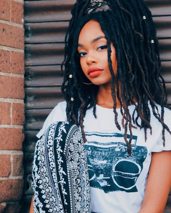 Chica afroamericana con rastar peinadas en una coleta con bandana 