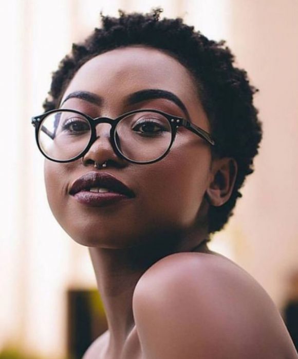 Chica afroamericana de piel morena, con lentes, cabello corto y afro con piercing en el septum