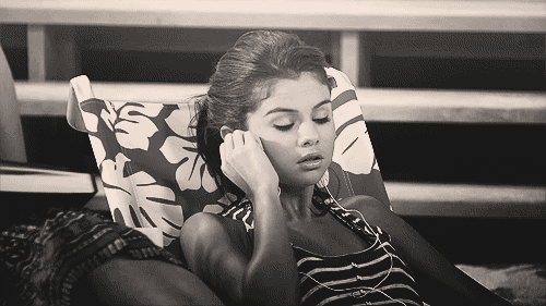 GIF Selena Gomez escuchando música mientras está sentada en un sofá