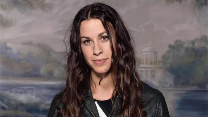 Alanis Morissette con la cabeza inclinada sonriendo ligeramente 