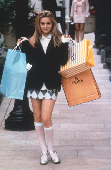 Cher de Clueless usando una falda de rombos, saco negro y calcetas blancas mientras va de compras 