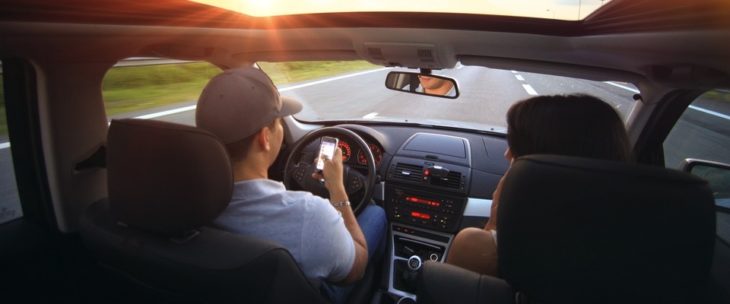 Hombre y mujer dentro de un automóvil leyendo un mensaje