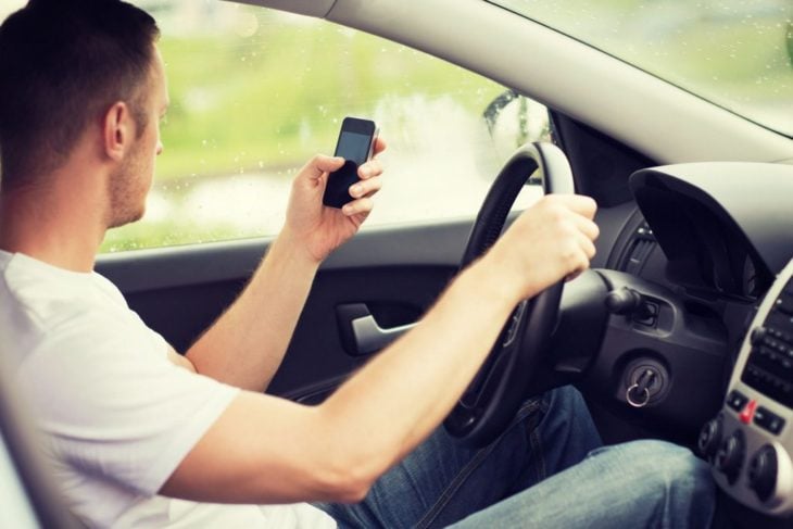 Hombre dentro de un automóvil leyendo un mensaje de texto 