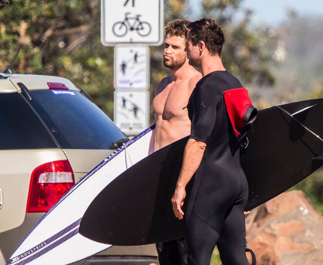 Liam y Chris Hemsworth usando trajes para surfear en Australia.