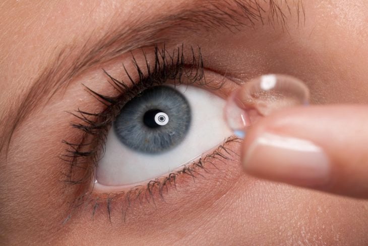 una mujer de ojos grises con una lente de contacto lista para colocarse