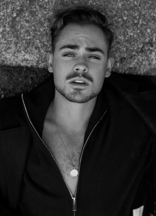 Fotos de Dacre Montgomery acostado, con bigote; fotografía en blanco y negro