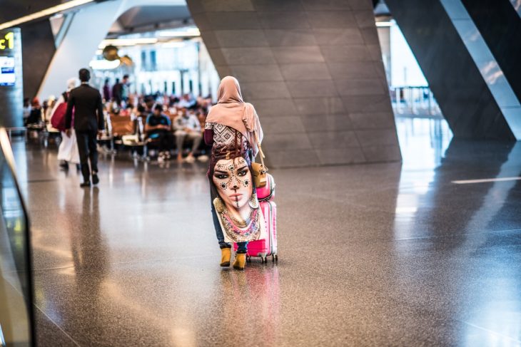 toma de espaldas de una mujer árabe que camina por un aeropuerto