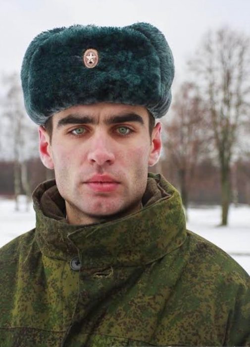 Hombre ruso guapo con gorro para el frío y chamarra militar, de ojos verde claro