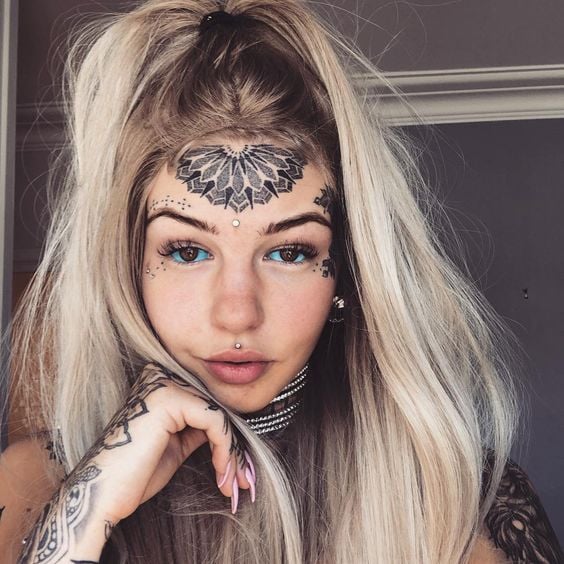Chica mostrando su tatuaje de mandala en el rostro