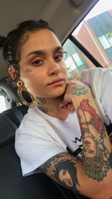 Chica timando una selfie de sus tatuajes en el rostro