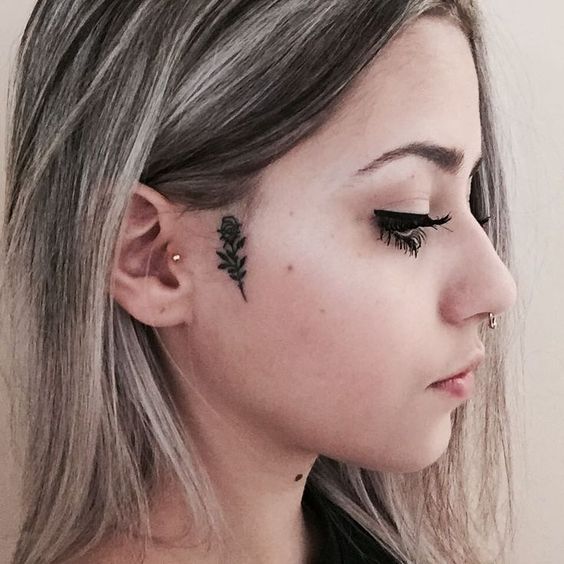Chica de perfil con una rosa tatuada al lado de las mejillas