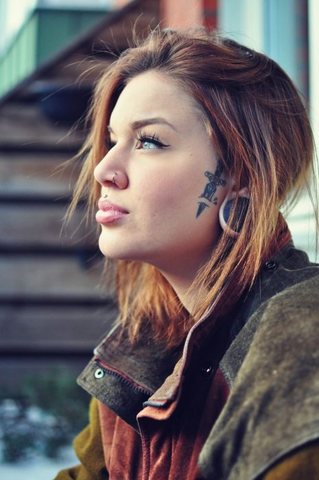 Chica de perfil mostrando su tatuaje de navaja al lado