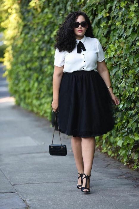 Atuendos para chicas plus size; chica de cabello chino con blusa blanca y falda a las rodillas negra