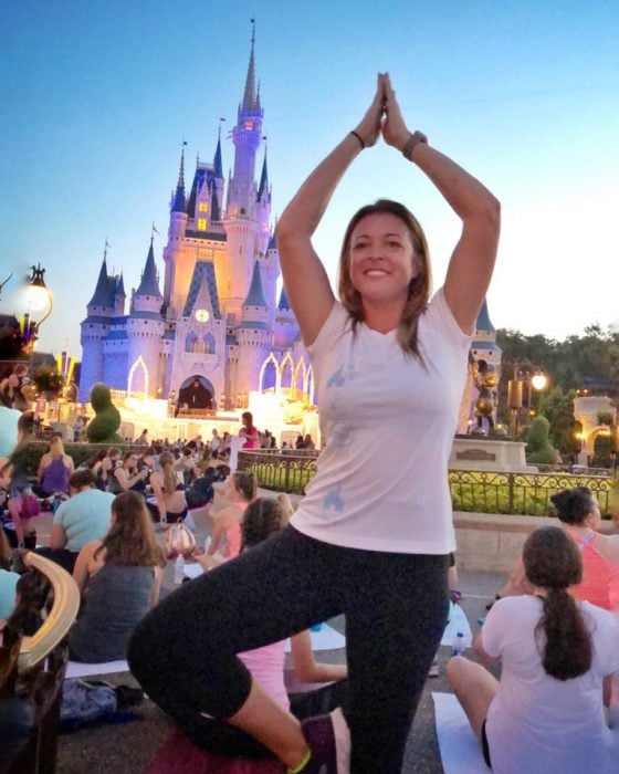Mujer haciendo una pose de Yoga mientras que está sucediendo el atardecer 