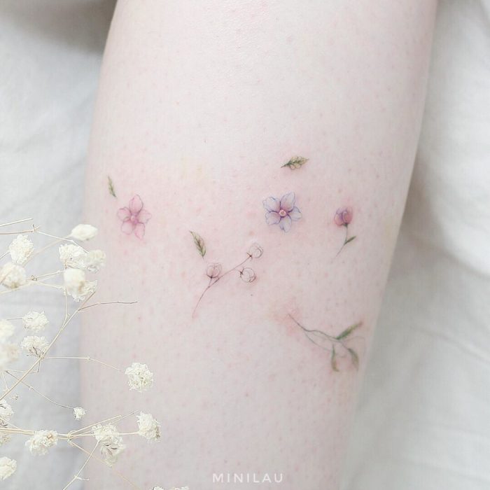 Chinese tattoo artist, Mini Lau;  Small, feminine tattoo with pastel colors of flowers and leaves