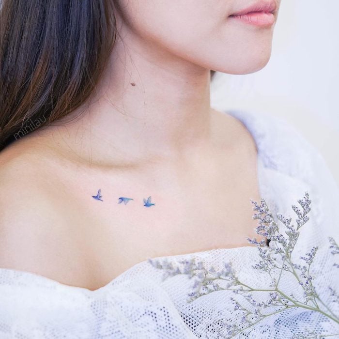 Tatuadora china, Mini Lau; tatuaje pequeño y femenino con colores pastel de aves azules volando en la clavícula