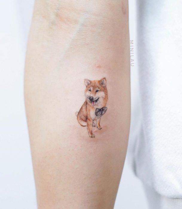 Tatuadora china, Mini Lau; tatuaje pequeño y femenino con colores pastel de perro shiba con moño