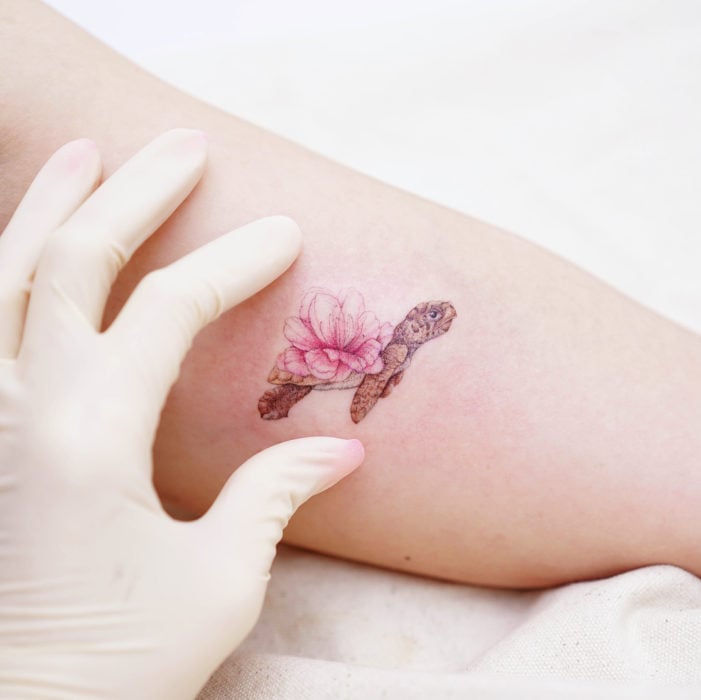 Tatuadora china, Mini Lau; tatuaje pequeño y femenino con colores pastel de tortuga con una flor rosa en el caparazón
