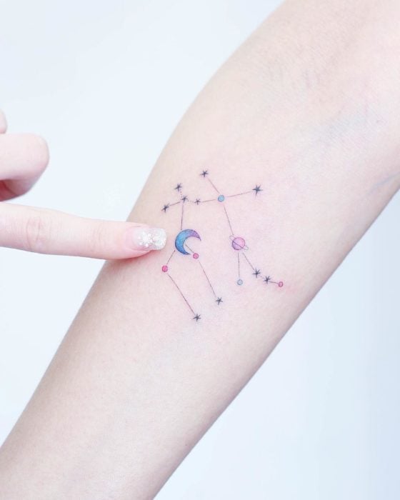 Chinese tattoo artist, Mini Lau;  Small, feminine tattoo with pastel colors of constellations with stars and planets