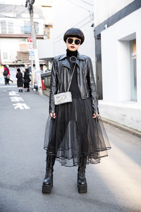 Moda japonesa harajuku; chica gótica con corte pixie, lentes redondos y grandes, chamarra de cuero con remaches, falda de tul y botas largas de plataforma