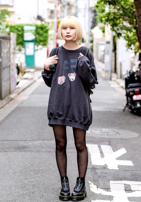 Moda japonesa harajuku; chica rubia con corte de hongo, con suéter oversized, medias de red y botas negras de plataforma