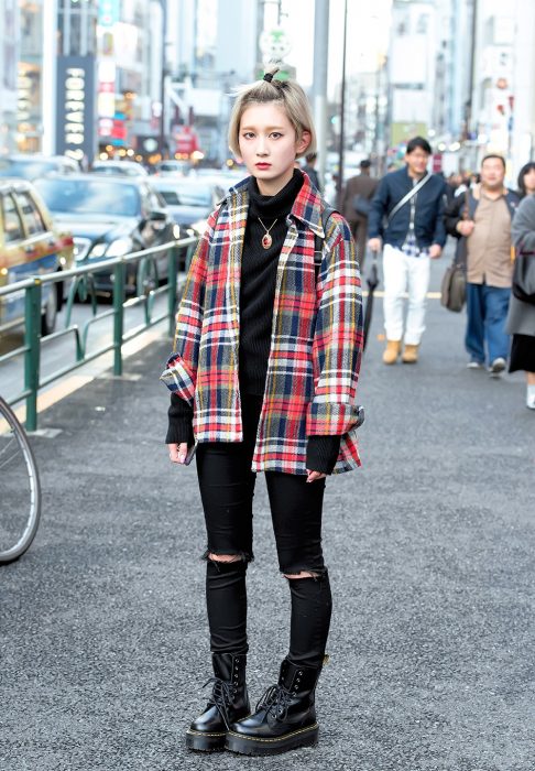 Moda japonesa harajuku; chica con estilo grunge, pantalones negros entubados, botas negras de trabajo y camisa de cuadros