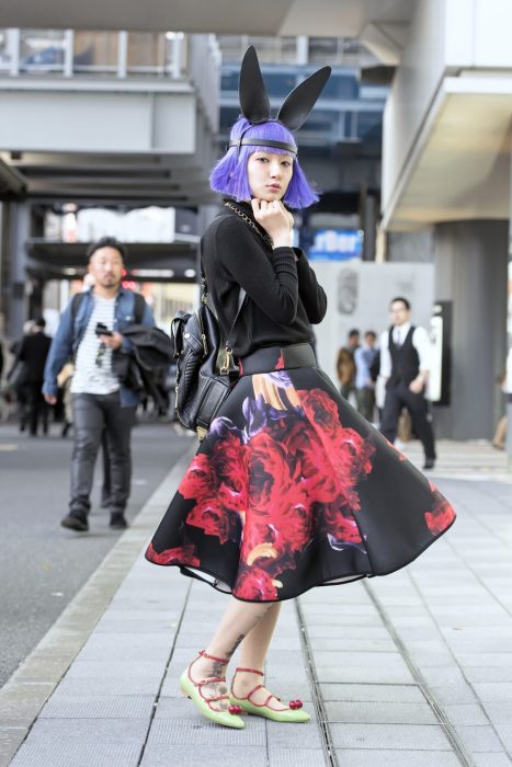 Moda japonesa harajuku; chica de cabello corto color morado, con orejas de conejo, suéter negro y falda floreada