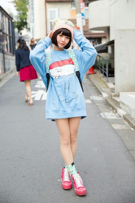 Moda japonesa harajuku; chica posando para foto en la calle, con suéter holgado kawaii de sushi y gorro tejido