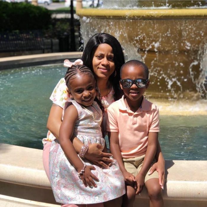 Madre sentada en una fuente junto a sus hijos posando para una fotografía